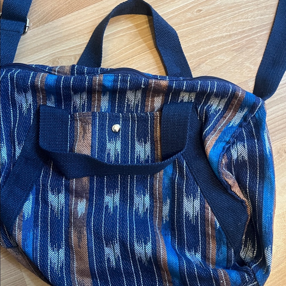 Blue and brown medium size material Duffel Bag tote Features zipper closure.